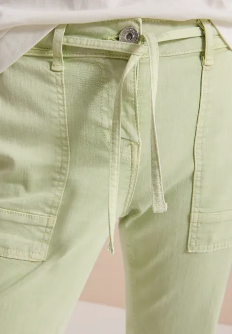 Hellgrüne Stoffhose mit Taillenschnürung und aufgesetzten Taschen.