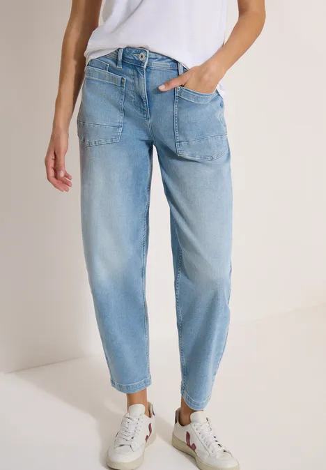 Barrel Leg Jeans mit aufgesetzten Taschen light blue used wash Eine Person trägt helle High-Waist-Jeans und weiße Sneaker vor neutralem Hintergrund.
