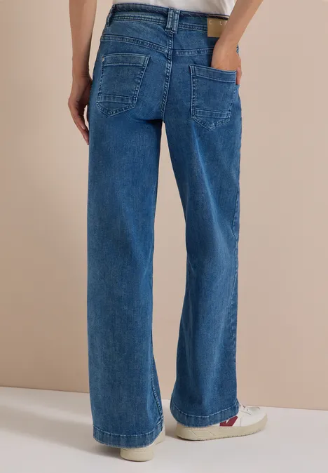 Vue de dos d’une personne portant un jean bleu large en denim, poches plaquées et coupe droite.