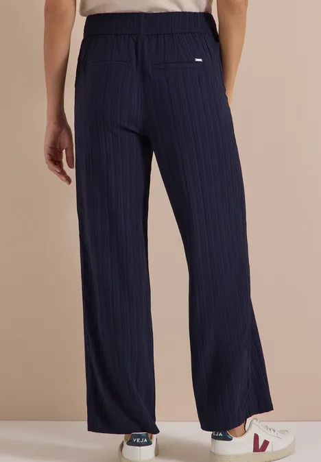 Wide Leg Hose mit Strukturstreifen urban dark blue Rückansicht einer Person in einer marineblauen, weiten, gestreiften Hose mit weißen Sneakern.