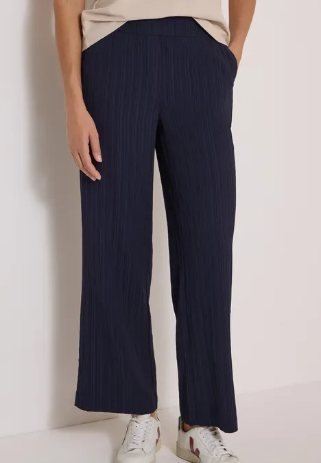 Wide Leg Hose mit Strukturstreifen urban dark blue Frau trägt marineblaue, gestreifte, weit geschnittene Hose mit Taschen und weißen Sneakers.