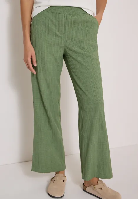Grüne, weit geschnittene Hose mit feinen Streifen und seitlichen Taschen.
