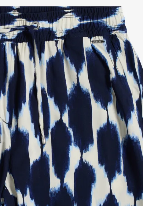 Gros plan sur une jupe plissée à motif abstrait blanc et bleu, effet coups de pinceau.