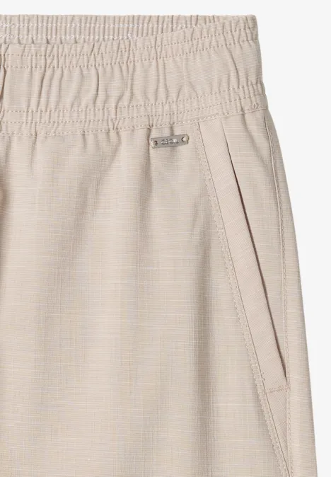 Gros plan d’un pantalon beige à taille élastique et poche latérale zippée.