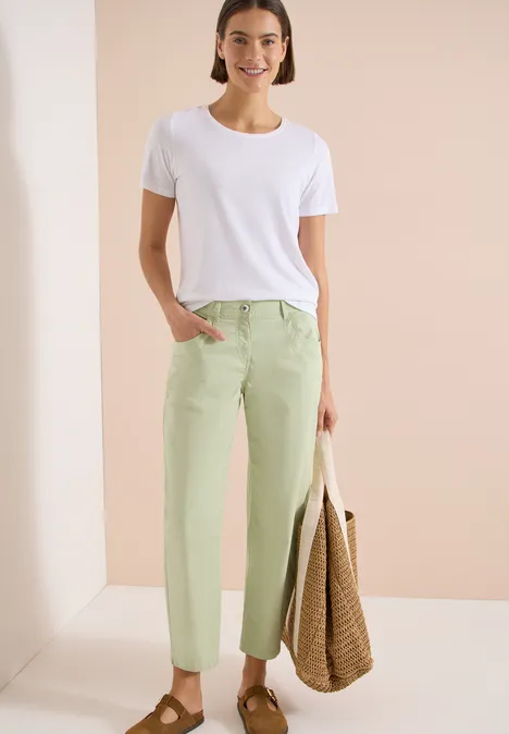 Barrel Leg Hose in Papertouch Qualität raw matcha lime Frau trägt weißes T-Shirt, mintgrüne Hose und hält großen geflochtenen Shopper vor hellem Hintergrund.