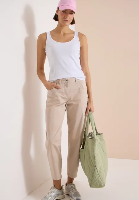 Barrel Leg Hose in Papertouch Qualität cashmere beige Frau in weißem Top, beigen Hosen und weißen Sneakers hält eine große hellgrüne Tragetasche.