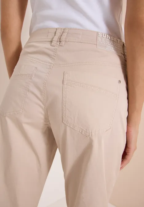 Barrel Leg Hose in Papertouch Qualität cashmere beige Rückansicht einer Person in hellbeigen, taillierten Jeans mit weißem Oberteil vor hellem Hintergrund.