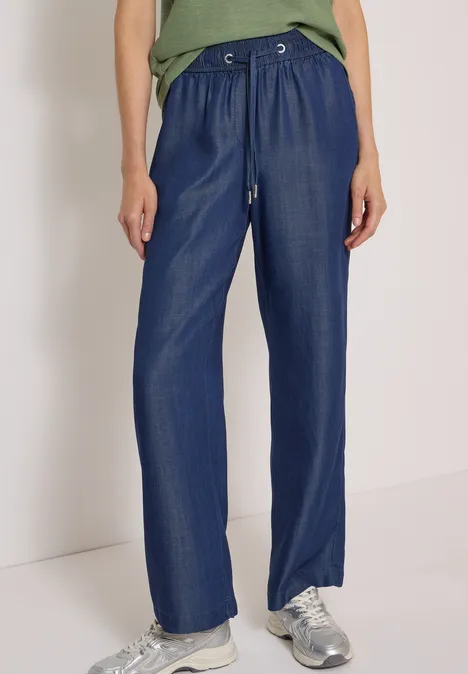 Locker sitzende, weite blaue Hose mit Tunnelzugbund und silbernen Sneakers.