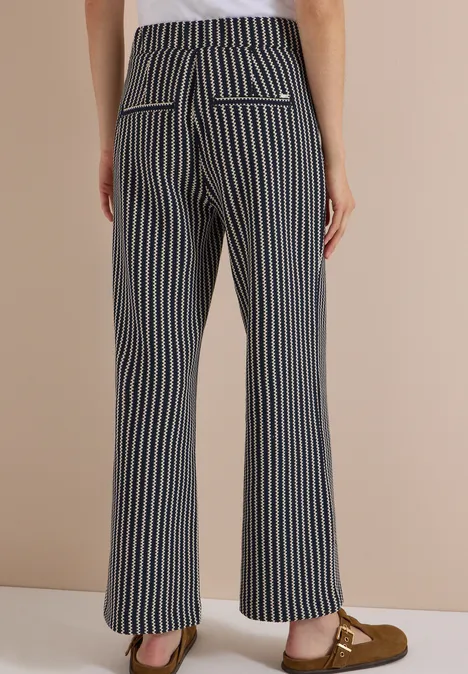 Rückansicht in ausgestellten Hosen mit blauen und weißen Streifen, Pattentaschen und Mokassins.