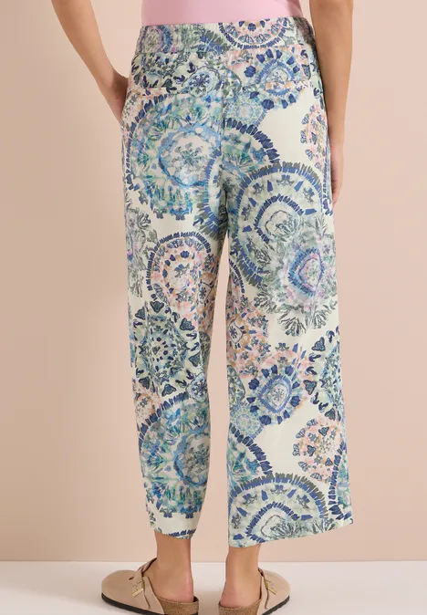 High Waist Wide Leg Hose im Loose Fit vanilla white Frau trägt locker sitzende, weit geschnittene Hose mit blau-grünem Mosaikmuster.