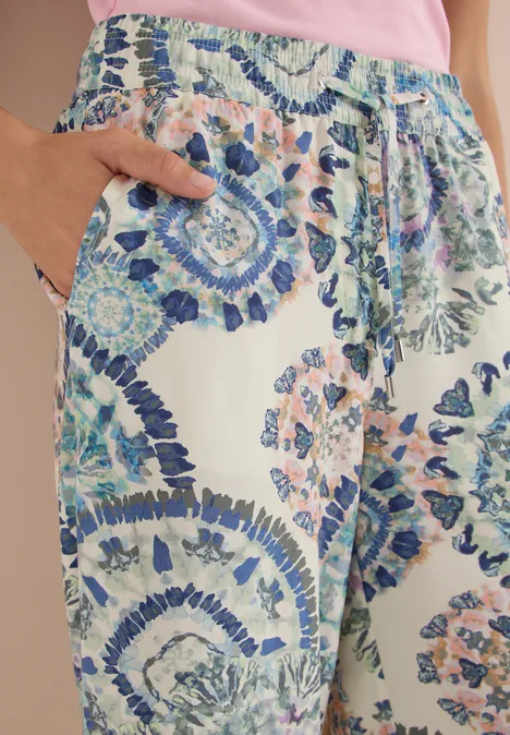 High Waist Wide Leg Hose im Loose Fit vanilla white Helle Sommerhose mit buntem Mosaikmuster in Pastelltönen, lockere Passform, Hand in Tasche.