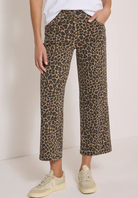 High Waist Wide Leg Jeans mit Leo-Muster creamy mocha Person trägt weit geschnittene, knöchellange Hose mit Leopardenmuster und hellen Sneakern.