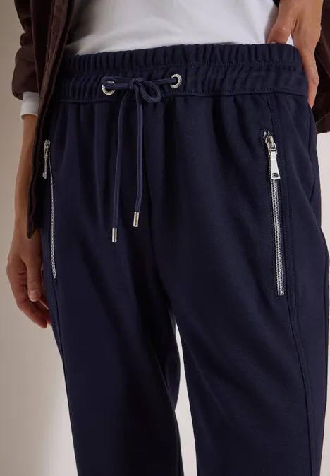 Pantalon de jogging bleu marine à taille élastique, cordon de serrage et poches zippées latérales.