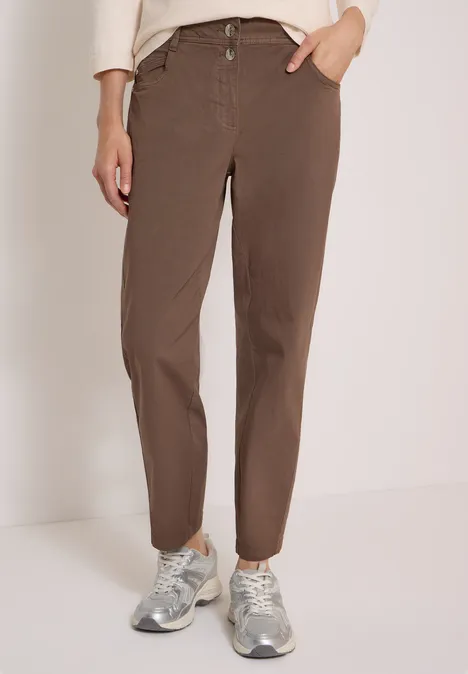 Mid Waist Barrel Leg Hose im Casual Fit urban taupe Persoon in bruine, rechte broek en zilverkleurige sneakers tegen neutrale achtergrond.