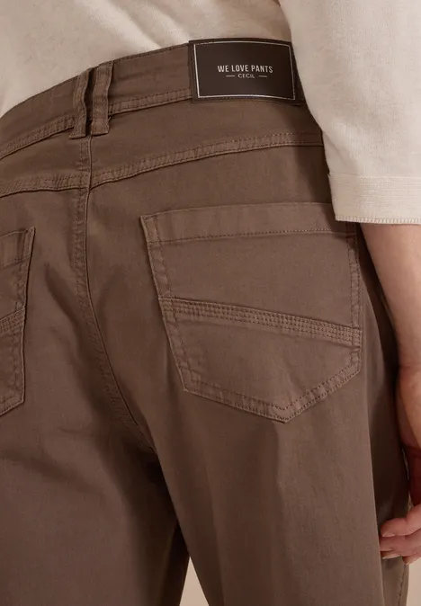 Mid Waist Barrel Leg Hose im Casual Fit urban taupe Achteraanzicht van een bruine broek met achterzakken en label in de taille, gedragen met een licht shirt.