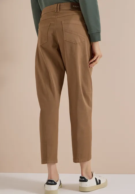 Vue de dos d’une personne portant un pantalon marron jusqu’aux chevilles et des baskets blanches à empiècement noir