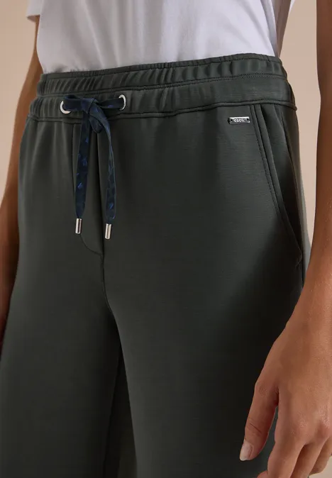 Spodnie z szerokimi nogawkami z tkaniny o fakturze przypominającej Silk Touch faded olive Ciemnozielone spodnie dresowe z elastycznym pasem, sznurkiem i kieszeniami bocznymi, zestawione z białym T-shirtem.
