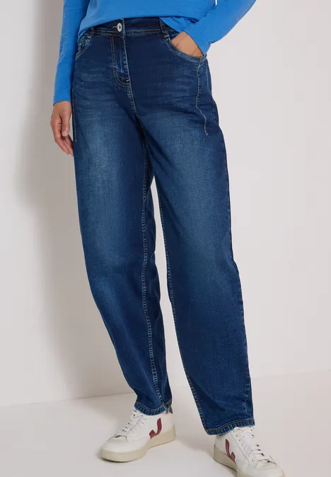 Jeans met High Waist en wijd uitlopende pijpen in een Loose Fit-pasvorm mid blue used wash Benen in donkerblauwe, wijdvallende jeans met hoge taille en witte sneakers.