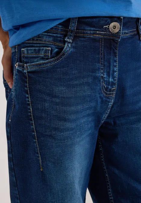 Jeans met High Waist en wijd uitlopende pijpen in een Loose Fit-pasvorm mid blue used wash Close-up van een persoon in donkerblauwe spijkerbroek met knoop, rits en voorzakken.