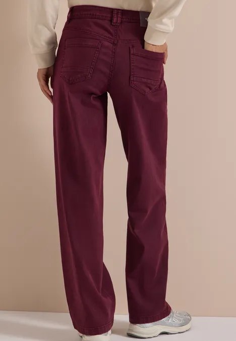Rückansicht einer Person in schlichten, weinroten, gerade geschnittenen Jeans.