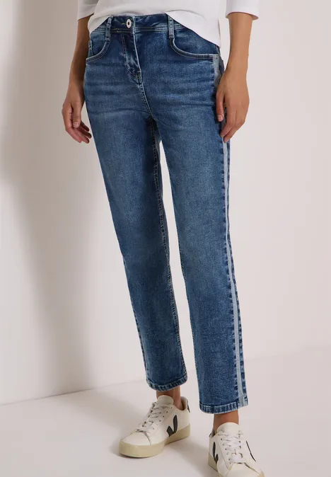 Gerade geschnittene blaue Jeans bis knapp über den Knöchel, kombiniert mit weißen Sneakern.