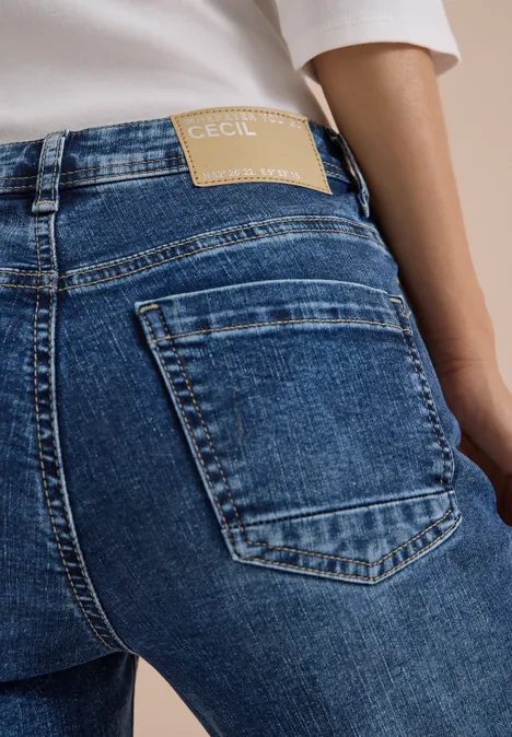 Rückansicht einer Person in blauen Jeans mit Markenlabel am Bund.