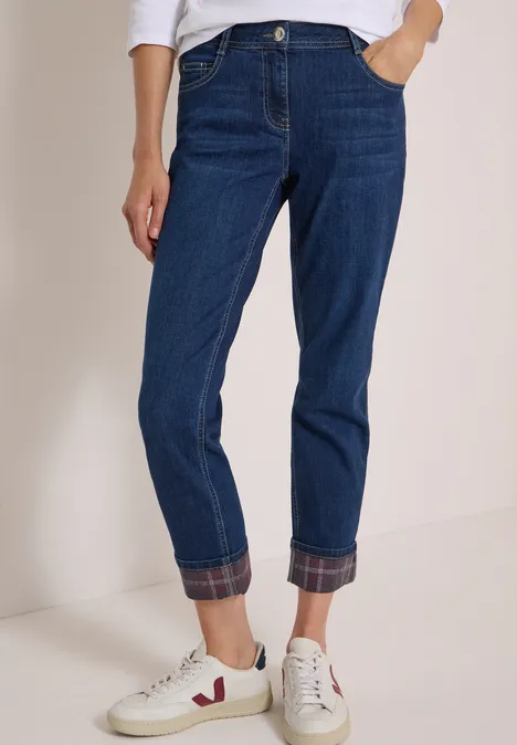 Blaue Jeans mit umgekrempeltem Saum, kombiniert mit weißen Sneakern.