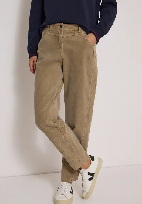 Mid Waist Barrel Leg Hose im Casual Fit creamy mocha Beige Cordhose mit hohem Bund, Seitentaschen und weißen Sneakern.
