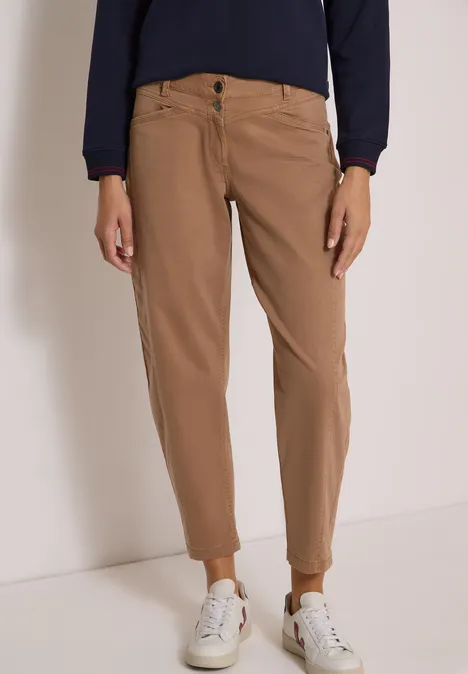 Bruine chino in ontspannen pasvorm, gecombineerd met witte sneakers.