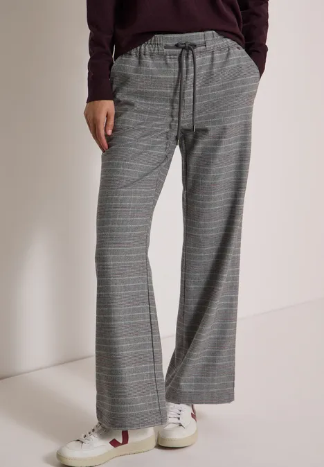 Grijze geruite broek met trekkoord, wijde pijpen, gecombineerd met witte sneakers.