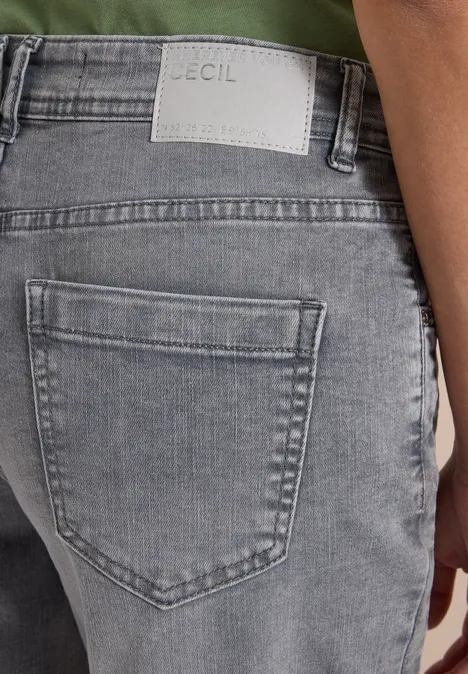 Rückansicht einer Person in grauen Jeans mit Markenlabel über der Gesäßtasche.