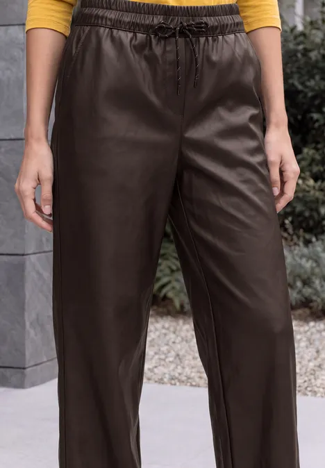 Broek met High Waist en Wide Leg pijpen in leerlook truffle brown Person trägt lockere, dunkelbraune Lederhose mit elastischem Bund.