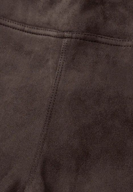 Gros plan sur un tissu suédé/velours brun foncé avec couture décorative apparente.