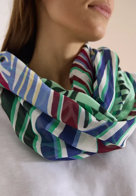 Une femme porte un foulard infinity à rayures colorées autour du cou.