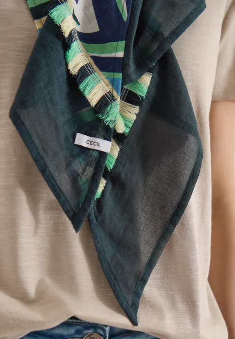 Foulard léger noir à franges vertes et beiges, étiquette “CECIL”, porté sur un haut beige.