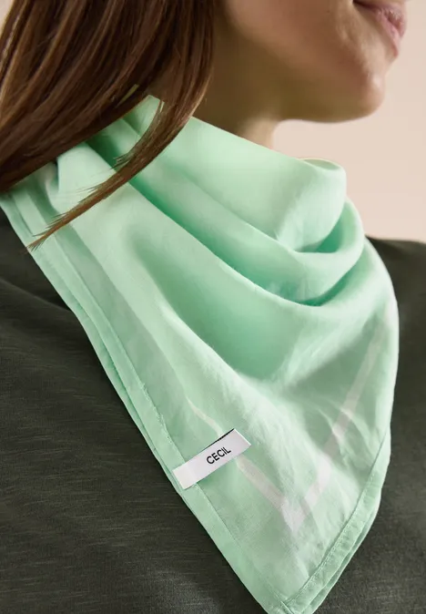 Iemand draagt een driehoekige, muntgroene sjaal met een klein label.