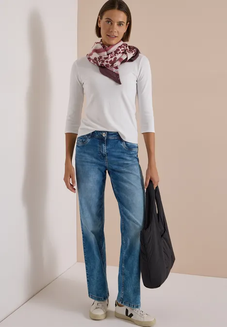 Dreieckstuch mit Leo-Muster berry red Frau trägt weiße Bluse, blaue Jeans, gemusterten Schal und hält eine schwarze Tasche.