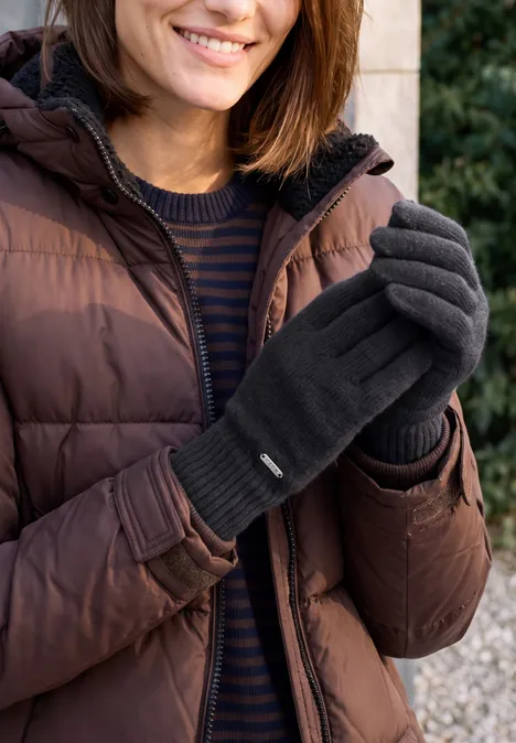 Handschoenen met gemêleerd effect dark navy blue Frau in brauner Steppjacke, gestreiftem Pullover und grauen Handschuhen lächelt im Freien.