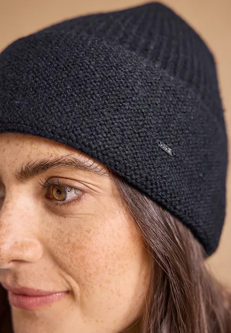 Nahaufnahme einer jungen Frau mit einem dunkelblauen Strick-Beanie und braunen Augen.