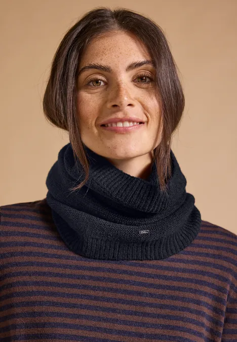 Loop-Schal in Melange-Optik dark navy blue Lächelnde Frau mit dunkelblauem Strickschal und gestreiftem Pullover vor beigem Hintergrund.