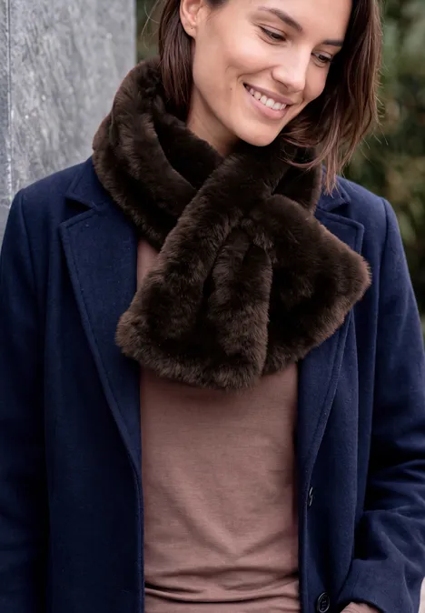 Fake Fur Schal in Unifarbe chocolate sauce brown Frau in dunkelblauem Mantel und braunem Kunstpelzschal lächelt im Freien.