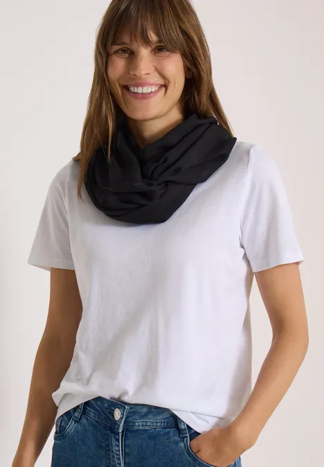 Effen Loop-sjaal Black Eine lächelnde Frau trägt weißes T-Shirt und schwarzen Loop-Schal.