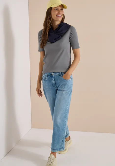 Effen Loop-sjaal urban dark blue Frau in grauem T-Shirt, blauen Jeans, gelber Kappe und Schal vor neutralem Hintergrund.