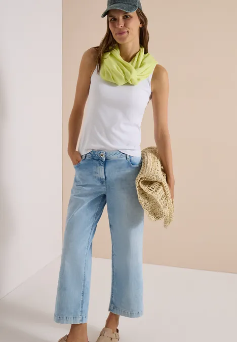 Effen Loop-sjaal citrin green Frau in weißem Top, hellblauen Jeans, neongrünem Halstuch und Cap, mit Strohtasche in der Hand.