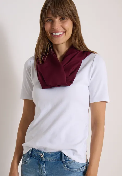 Effen Loop-sjaal red wine Lächelnde Frau in weißem T-Shirt, blauen Jeans und weinrotem Schal.