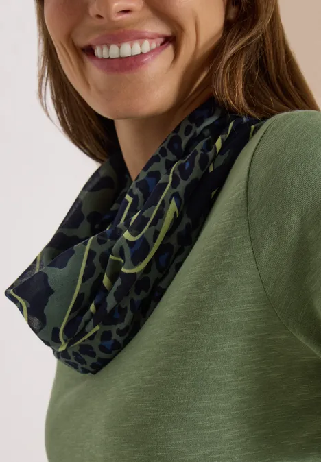Loop-sjaal met luipaardprint dried olive green Lächelnde Frau in grünem Shirt mit dunkelgrünem, leopardähnlichem Rundschal.