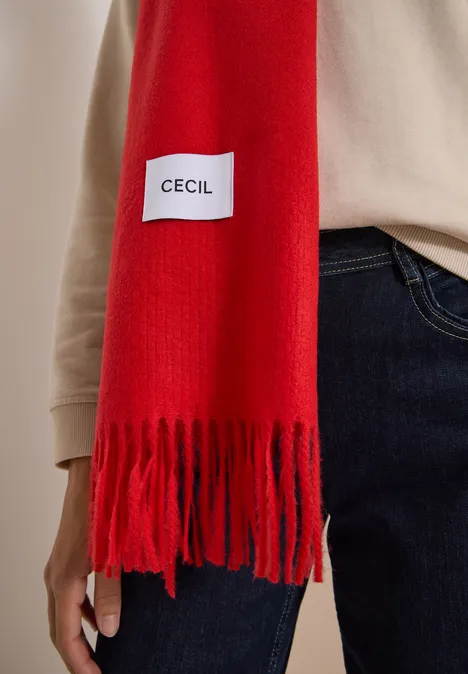 Roter Schal mit Fransen und "Cecil"-Label, getragen über einem beigen Pullover und Jeans.