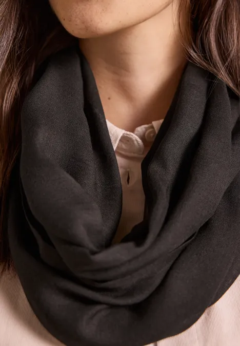 Effen Loop-sjaal truffle brown Iemand draagt een zwarte, zachte colshawl rond de hals.