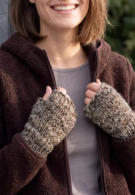 Mouliné Stulpen truffle brown Nahaufnahme einer lächelnden Person in Fleecejacke und gestrickten Handstulpen, die die Jacke hält.