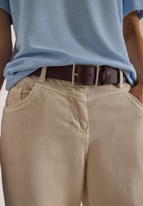 Ceinture Basic à boucle carrée Raisin Person trägt beige Hose mit Taschen, hellblaues Shirt und braunen Ledergürtel